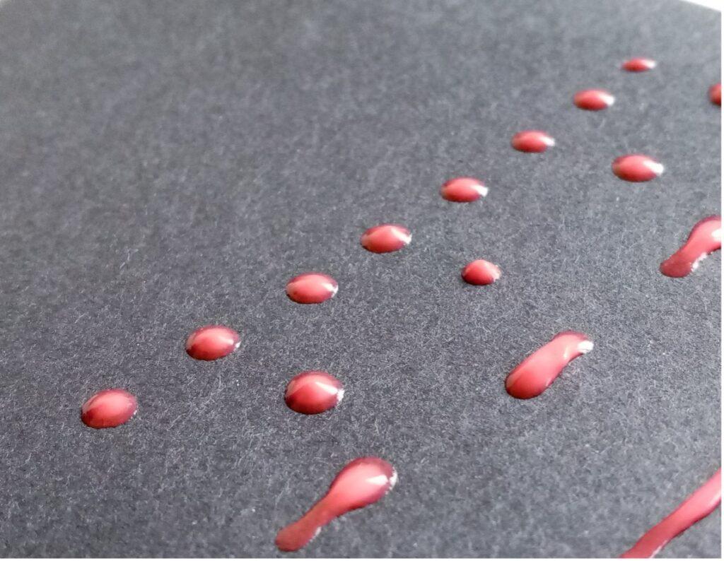 Close up image of dried red glue, spread in dotted and dashed lines.